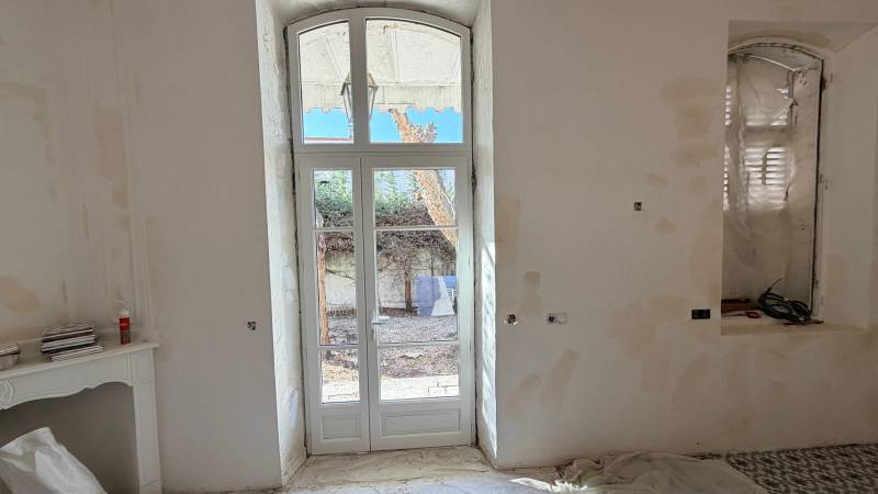 Pose d'une fenêtre PVC en rénovation par un menuisier certifié RGE dans une maison ancienne à Nîmes.